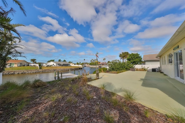 view of yard with a water view, a patio, and a boat dock