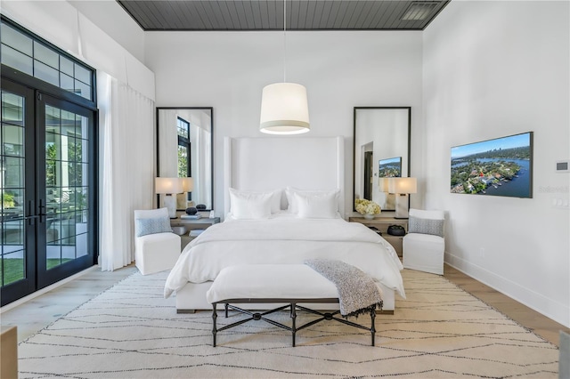 bedroom featuring light hardwood / wood-style floors, a high ceiling, and french doors