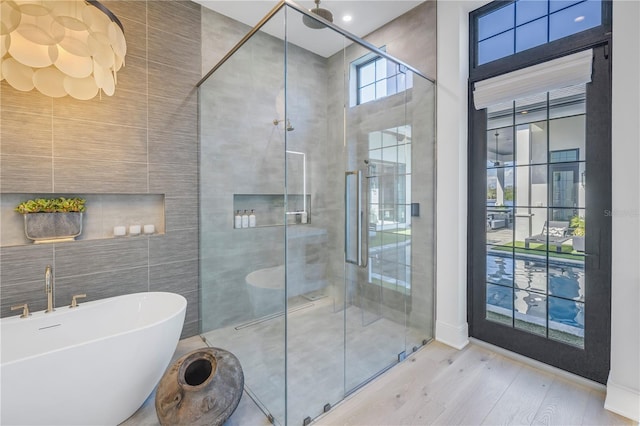 bathroom featuring independent shower and bath, wood-type flooring, and tile walls