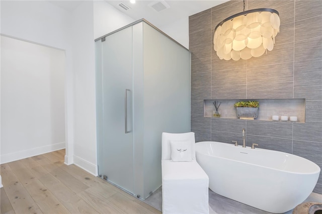 bathroom featuring a tub to relax in, tile walls, and hardwood / wood-style flooring