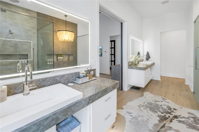 bathroom with hardwood / wood-style floors, vanity, a shower with door, and a notable chandelier