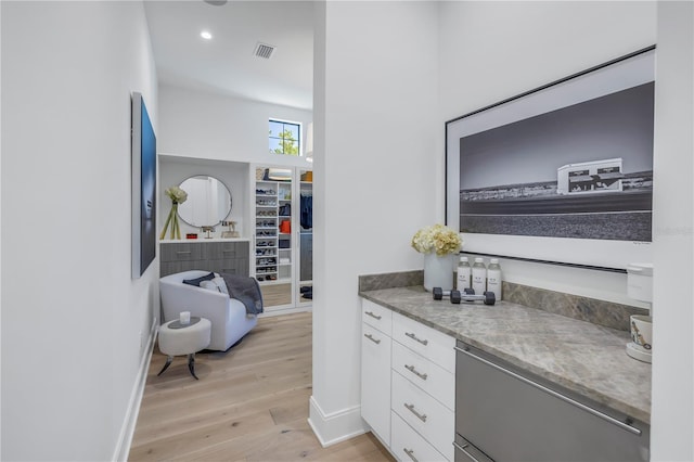 interior space featuring stainless steel fridge, light hardwood / wood-style floors, and white cabinetry