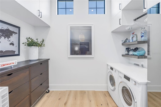 laundry area with washing machine and clothes dryer, a towering ceiling, cabinets, and light wood-type flooring