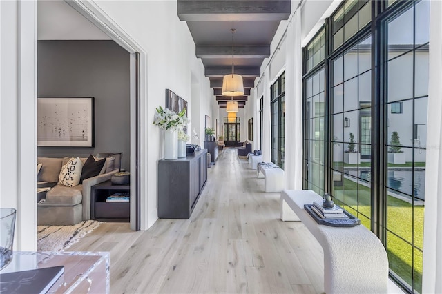 hall featuring beam ceiling, a towering ceiling, and light hardwood / wood-style floors