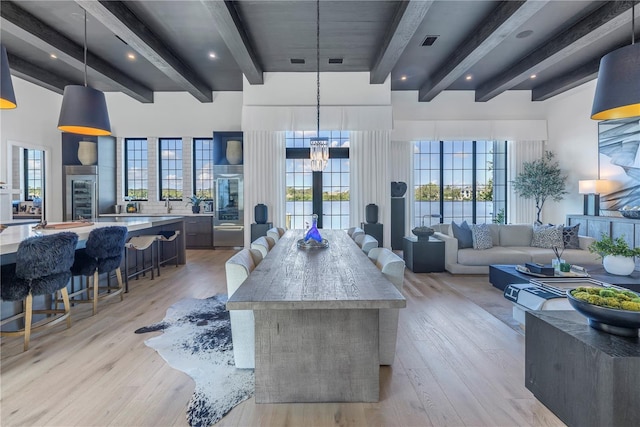 interior space with hanging light fixtures, beamed ceiling, a spacious island, and plenty of natural light