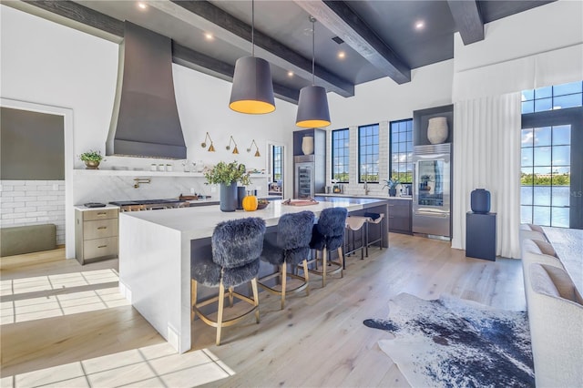 kitchen featuring plenty of natural light, decorative light fixtures, wall chimney range hood, and a breakfast bar