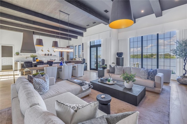 living room with beam ceiling, hardwood / wood-style floors, french doors, and a high ceiling