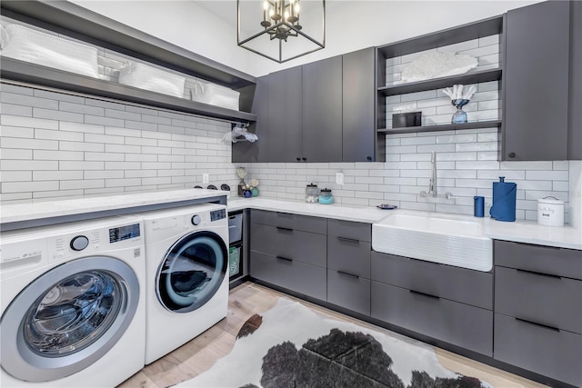 washroom with separate washer and dryer, sink, a chandelier, and light wood-type flooring