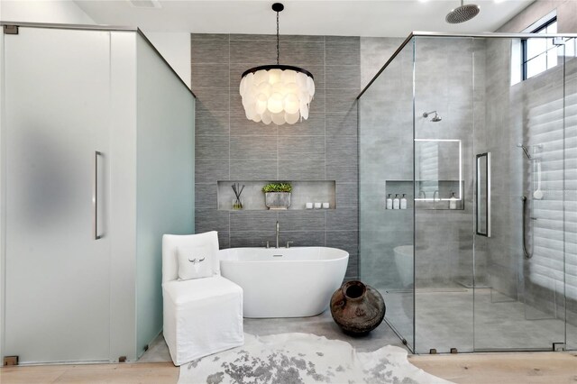 full bath with a soaking tub, a shower stall, and tile walls