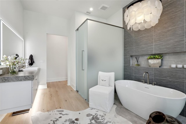 full bathroom with vanity, visible vents, tile walls, a soaking tub, and a stall shower