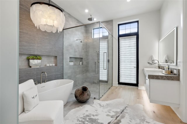 full bathroom featuring a freestanding tub, wood finished floors, vanity, tile walls, and a shower stall