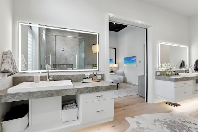 full bath featuring a stall shower, vanity, ensuite bath, and wood finished floors