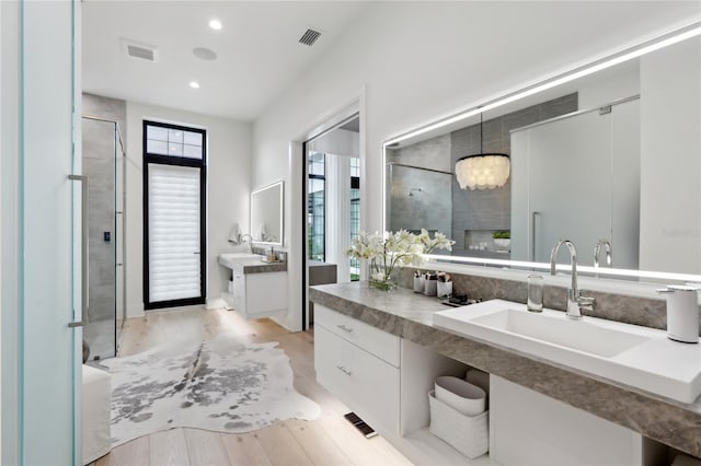 full bathroom featuring a stall shower, visible vents, wood finished floors, vanity, and recessed lighting