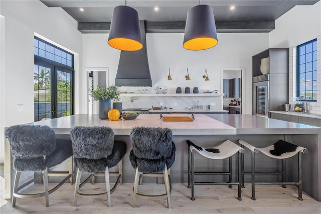 kitchen with open shelves, a towering ceiling, and a kitchen breakfast bar