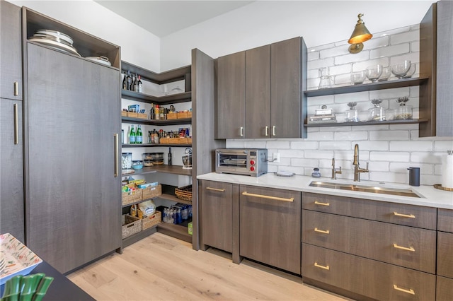 kitchen featuring light countertops, open shelves, a sink, and dark brown cabinetry