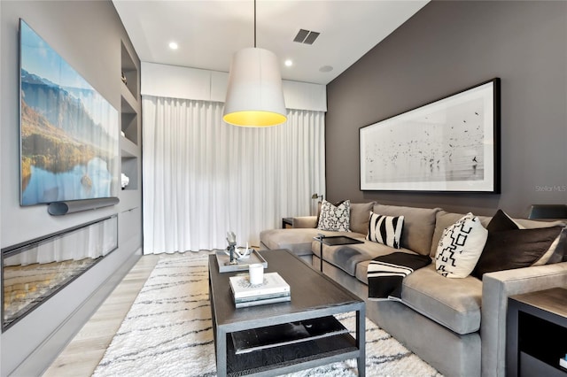 living room featuring light wood-style flooring, visible vents, and recessed lighting