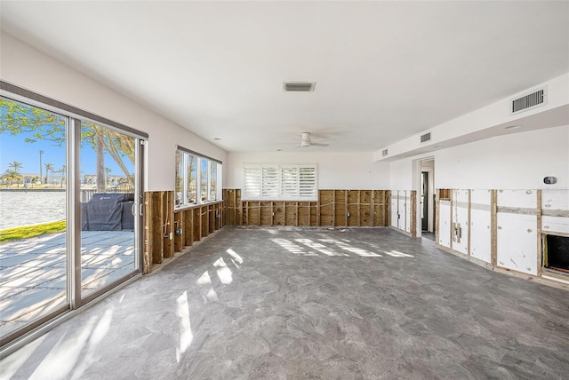 unfurnished room with ceiling fan and a water view