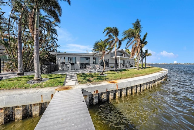 dock area featuring a lawn, a water view, and a patio