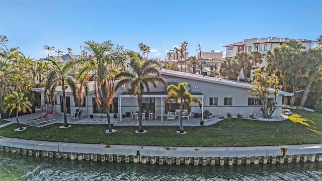 view of front of home with a patio, a water view, and a front lawn