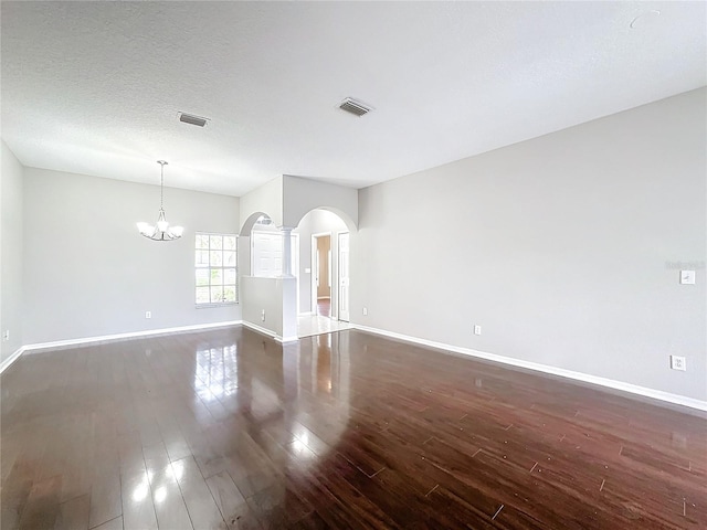 spare room with dark hardwood / wood-style flooring, a textured ceiling, and an inviting chandelier