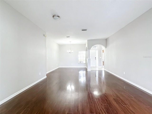 empty room with a chandelier and dark hardwood / wood-style floors