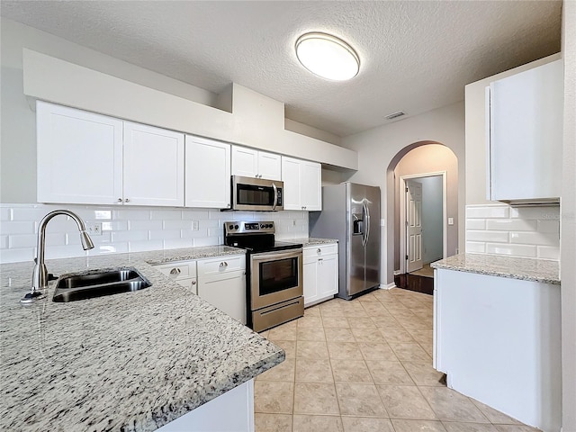 kitchen with stainless steel appliances, white cabinetry, sink, and backsplash