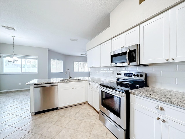 kitchen with tasteful backsplash, stainless steel appliances, sink, white cabinets, and kitchen peninsula