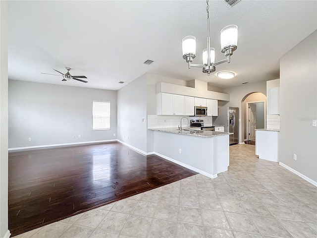 kitchen featuring stainless steel appliances, kitchen peninsula, decorative light fixtures, white cabinets, and light wood-type flooring