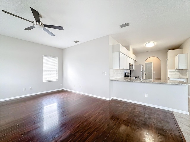 kitchen featuring dark hardwood / wood-style floors, white cabinetry, kitchen peninsula, and tasteful backsplash