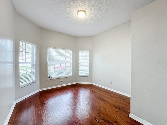 empty room with wood-type flooring and a textured ceiling