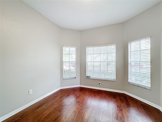 empty room featuring dark hardwood / wood-style flooring and a textured ceiling