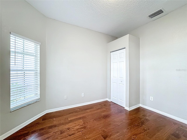 unfurnished bedroom featuring dark wood-type flooring and a textured ceiling