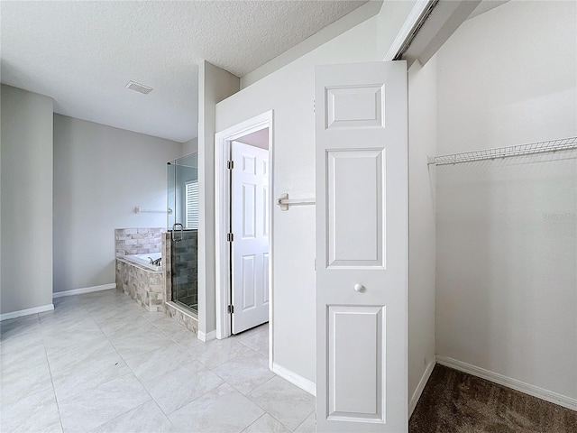 interior space with independent shower and bath and a textured ceiling