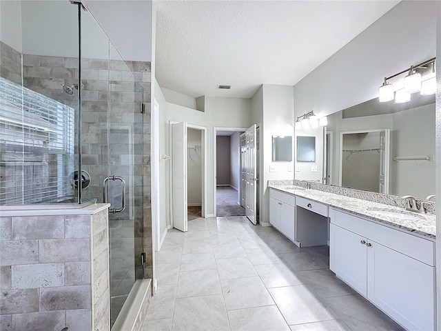 bathroom with tile patterned flooring, vanity, a textured ceiling, and a shower with door