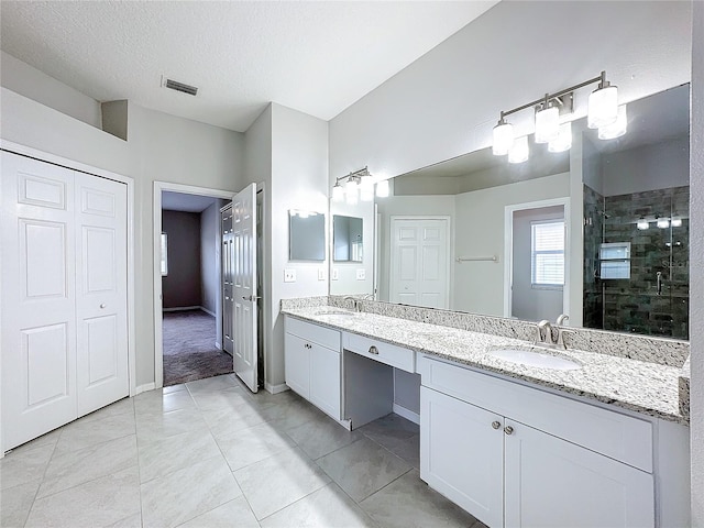 bathroom with vanity, a textured ceiling, tile patterned floors, and a shower with shower door