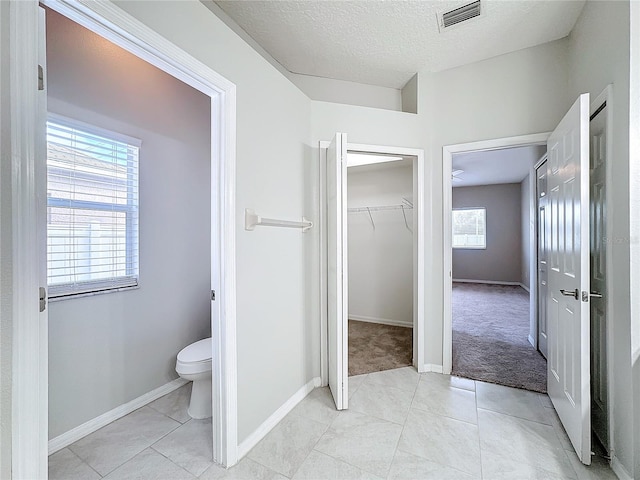 bathroom with toilet, a textured ceiling, and tile patterned floors