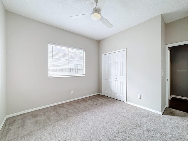 unfurnished bedroom featuring ceiling fan, light carpet, a closet, and a textured ceiling