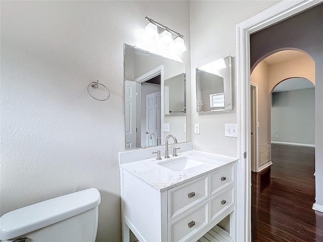 bathroom featuring toilet, vanity, and hardwood / wood-style flooring