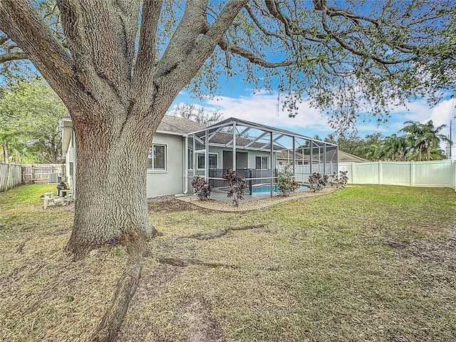 rear view of property featuring a fenced in pool, a yard, and glass enclosure