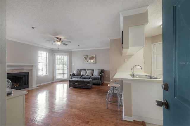 living room featuring a textured ceiling, hardwood / wood-style flooring, ceiling fan, and sink