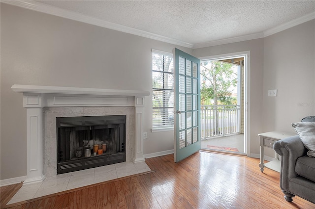 living room with a tile fireplace, a textured ceiling, light hardwood / wood-style floors, and crown molding