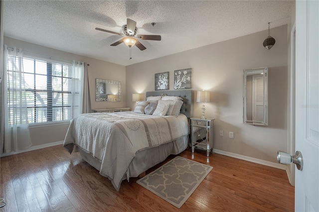 bedroom with hardwood / wood-style floors, a textured ceiling, and ceiling fan