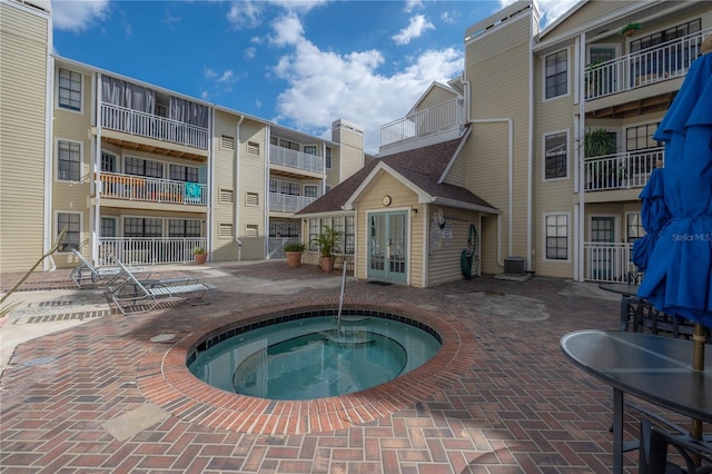 view of pool with a community hot tub, french doors, and central air condition unit