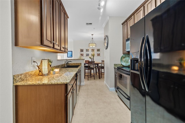 kitchen with black fridge, light stone counters, stainless steel electric range oven, hanging light fixtures, and sink