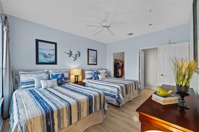 bedroom with a closet, light wood-type flooring, a spacious closet, and ceiling fan