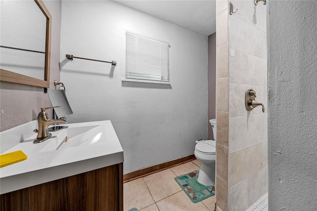 bathroom featuring tile patterned flooring, vanity, tiled shower, and toilet