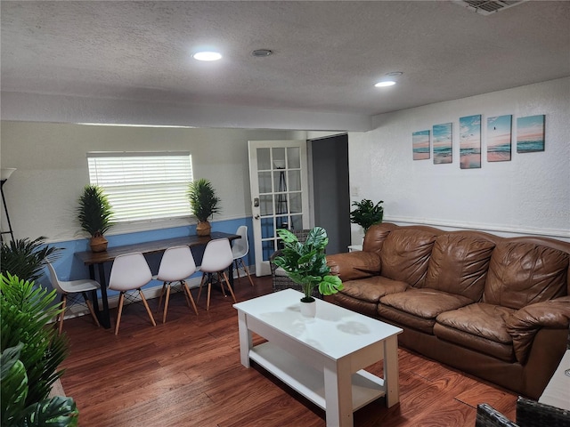 living room featuring french doors, a textured ceiling, and dark wood-type flooring