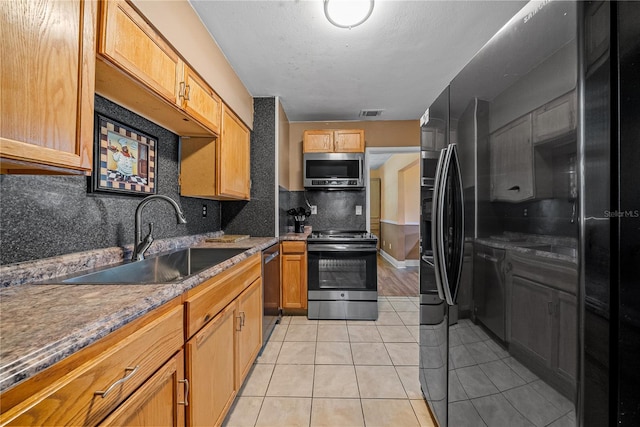 kitchen featuring sink, decorative backsplash, light stone countertops, light tile patterned floors, and stainless steel appliances