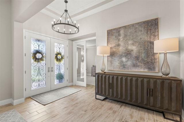 foyer entrance featuring french doors, a notable chandelier, and light hardwood / wood-style floors