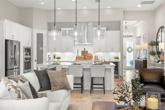 living room with light hardwood / wood-style floors, a high ceiling, wine cooler, and a notable chandelier